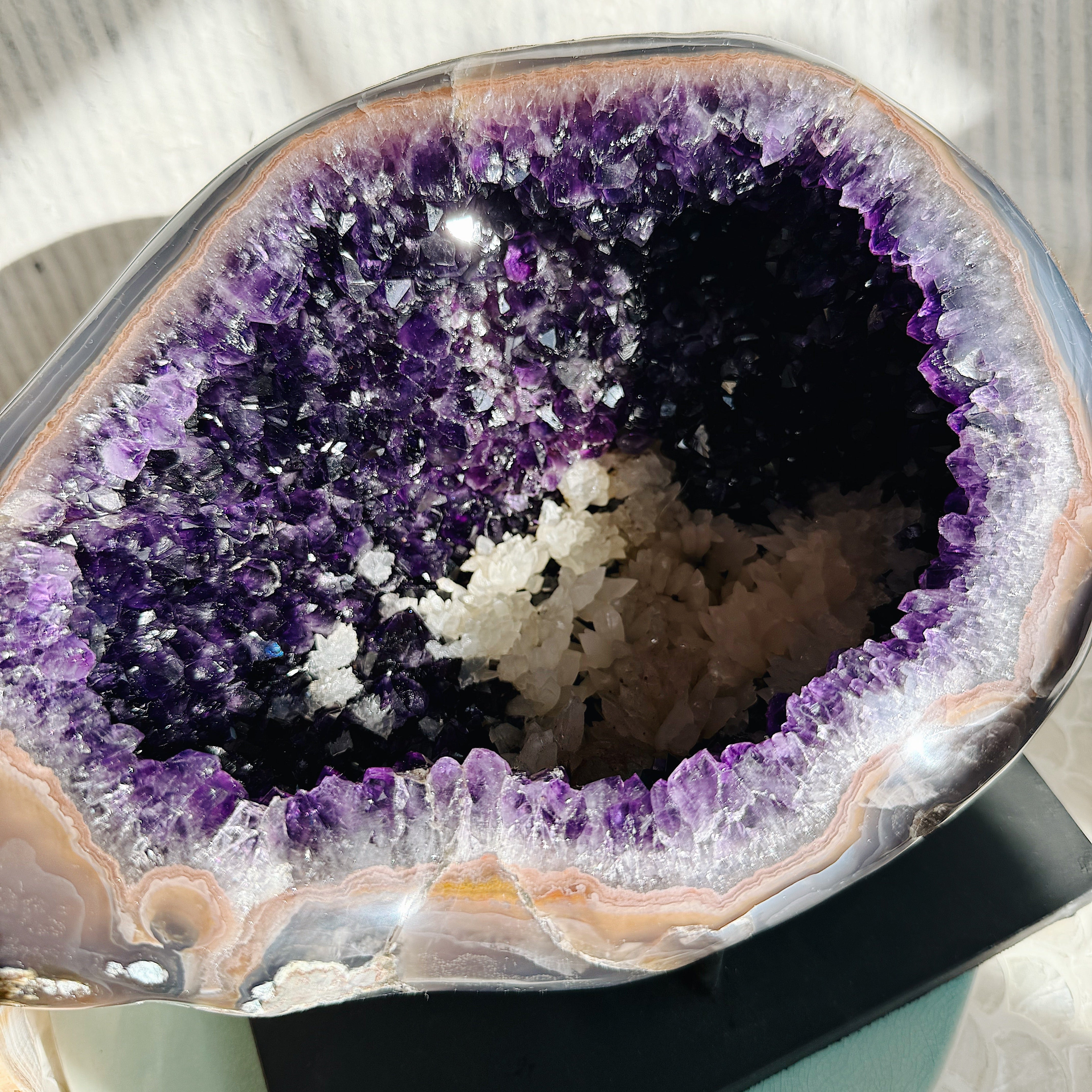 Raw Amethyst Druzy Cluster crystal with sparkling points, displayed on a neutral surface for decor or spiritual use.