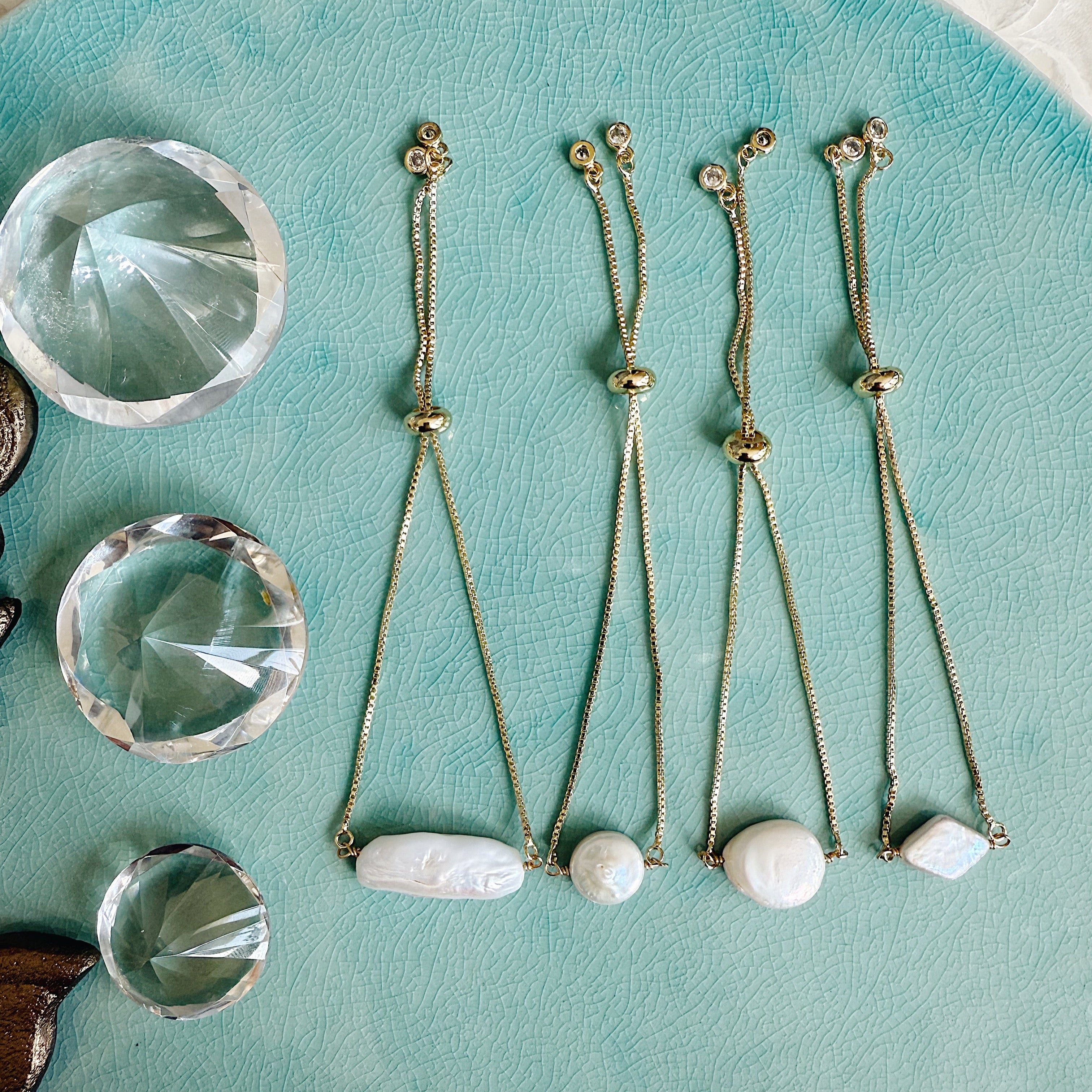 Close-up of The Kenny Bracelet with freshwater pearls and white topaz on a gold chain, styled in soft natural light for an elegant, coastal look.