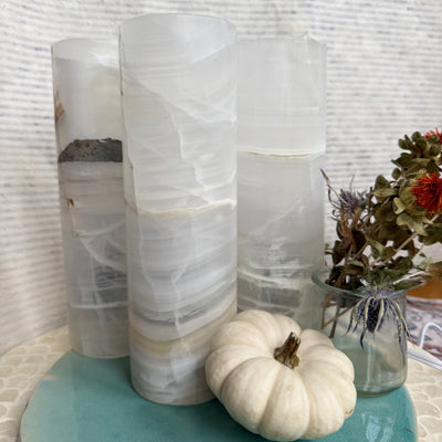 White Banded Onyx Cylinder Lamp glowing softly with layered natural stone patterns — symbolizing calm, grounding, and renewal from Wild Alabaster’s Autumn Alchemy Collection.”